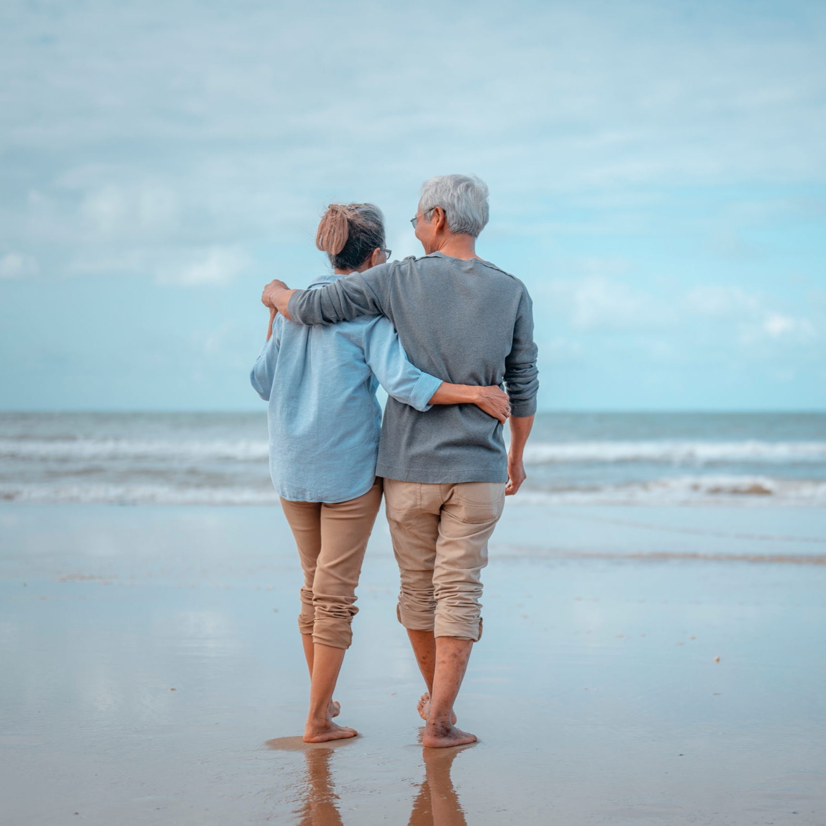 Senior couples walking on the beach at sunny day, plan life insurance with the concept of happy retirement.